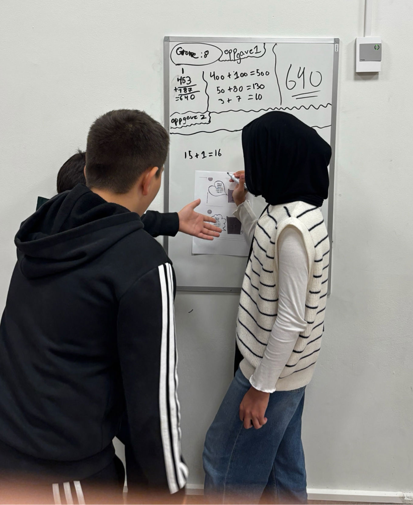 Et par barner som skriver på en whiteboard