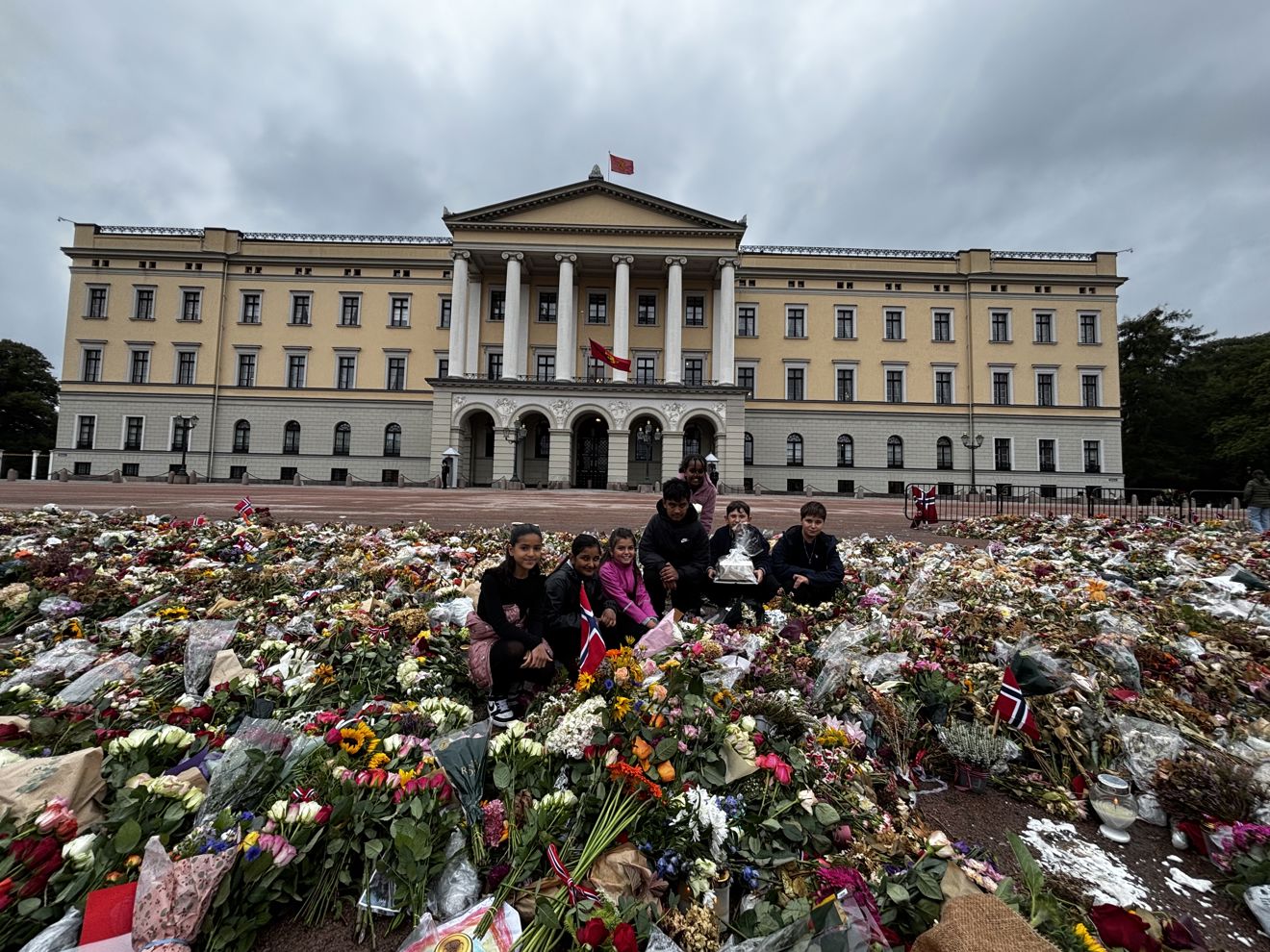 Elevrådet foran slottet i et hav med blomster og hilsener.